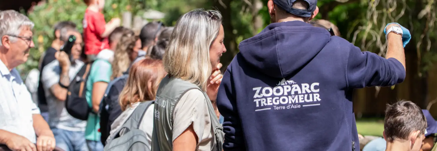 Visiteurs rassemblés autour d'un soigneur en sweat ZooParc de Trégomeur lors d'une animation
