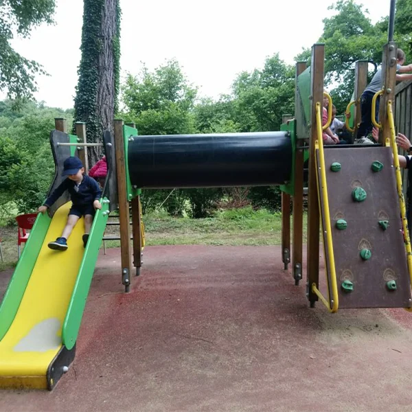 Aire de jeux du parc avec toboggan jaune, tunnel et mur d'escalade, un enfant glissant