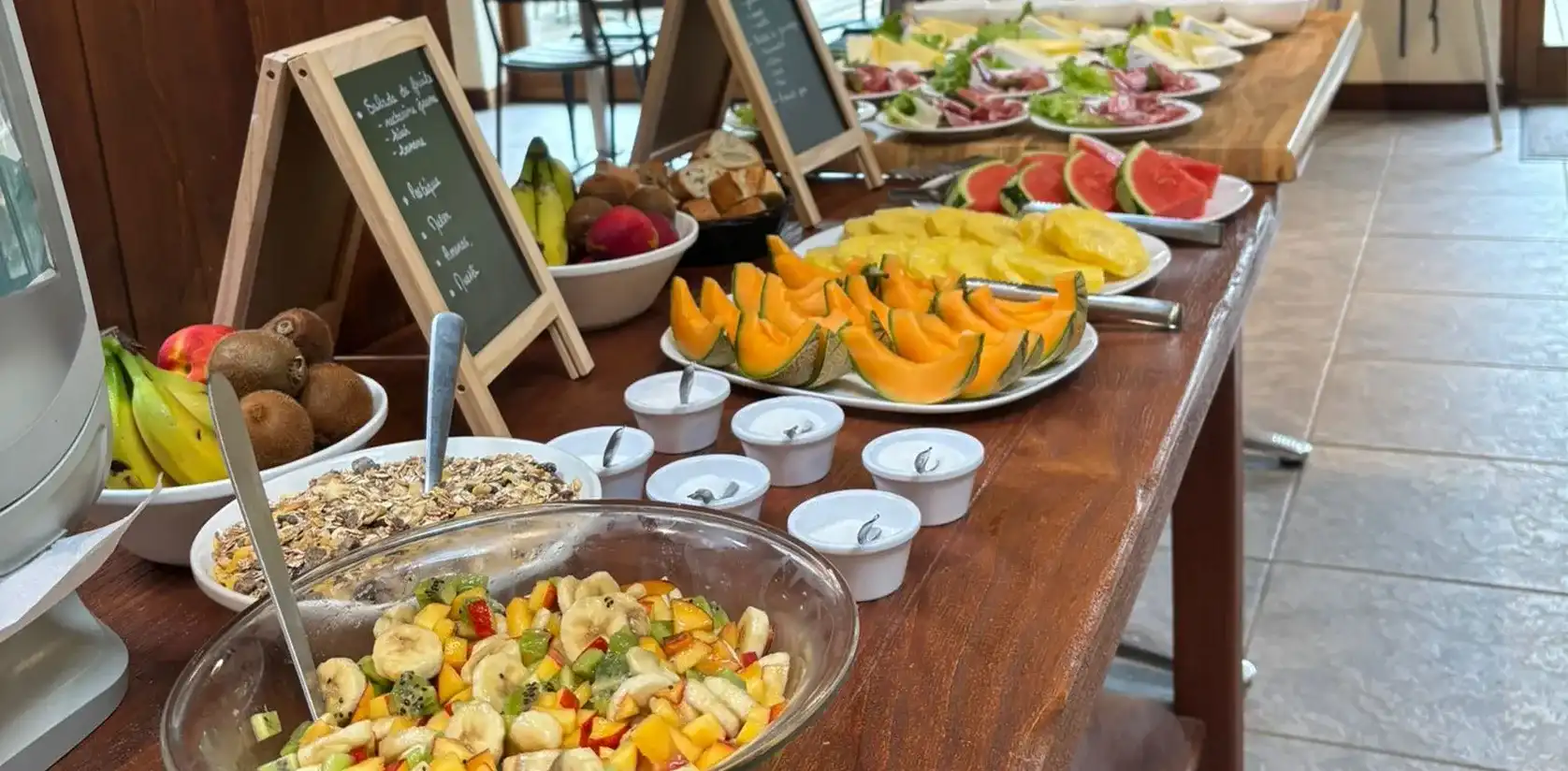 Buffet de brunch avec grand bol de salade de fruits, melon, pastèque et bananes