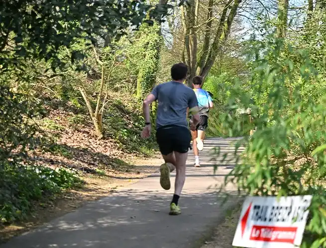 Coureur sur un chemin boisé du parc pendant la course Breizh Asia