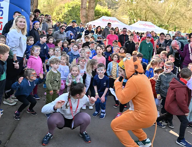 Échauffement des enfants avec la mascotte panda roux avant la course