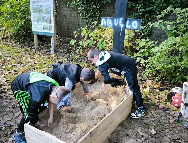 Enfants fouillant du sable dans un bac en bois lors d'une animation d'Halloween au parc