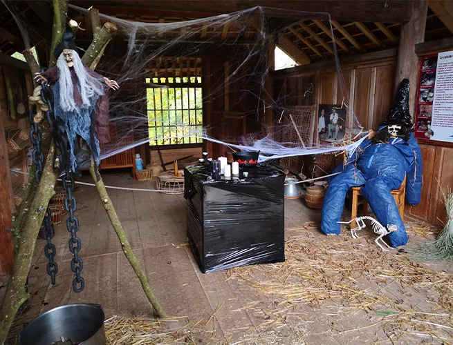 Cabane décorée pour Halloween avec toiles d'araignée, chaînes, paille et mannequin épouvantail