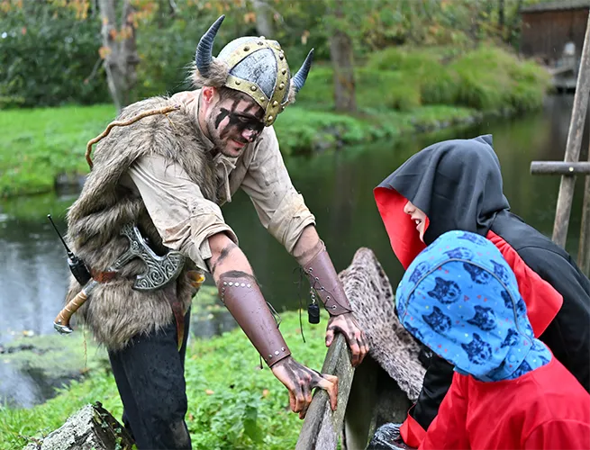 Personnage déguisé en Viking près d'une rivière avec des enfants déguisés pendant Halloween