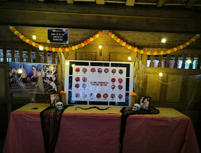 Stand d'Halloween avec écran, crânes et guirlandes orange dans un bâtiment en bois