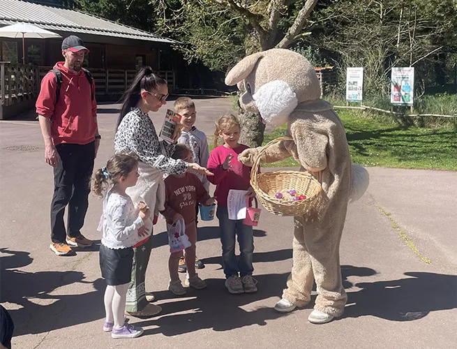 Mascotte lapin de Pâques et famille avec enfants sur une allée du parc lors de la chasse aux oeufs