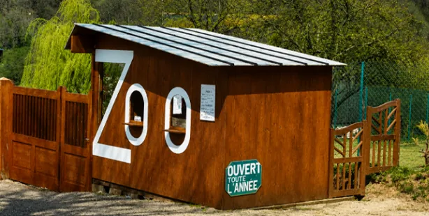 Brown wooden hut with the inscription Zoo and a sign reading "Open all year" at the entrance of the ZooParc