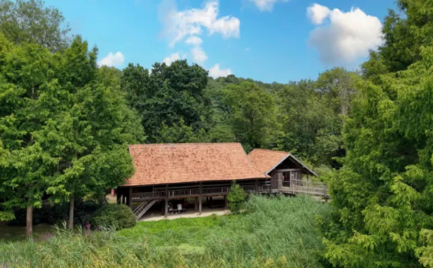 Mill with a red tile roof surrounded by trees and reeds at the ZooParc de Trégemeur