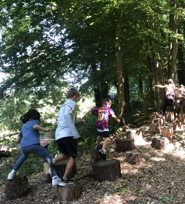 Children walking on a log trail in the forest
